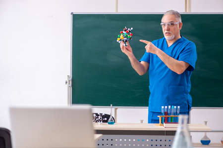 Old male teacher chemist in the classroom