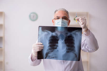 Old male doctor radiologist in vaccination concept