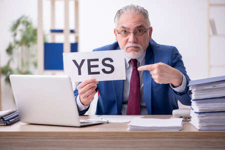 Old male employee and too much work in the officeの写真素材
