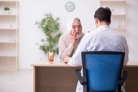 Old male patient visiting young male doctor dentistの写真素材