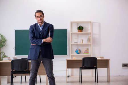 Young male teacher in front of green board