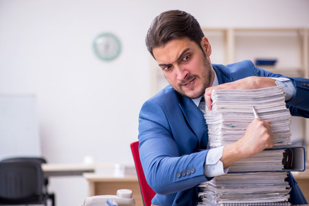 Young businessman employee and too much work in the officeの写真素材
