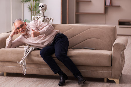 Old man sitting on the sofa with the female skeletonの写真素材