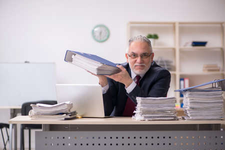 Aged male employee and too much work at workplaceの写真素材