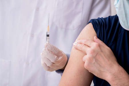Old male patient visiting young male doctor in vaccination conceの写真素材