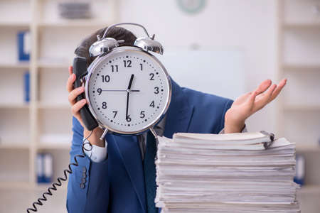 Young male employee in time management concept in the officeの写真素材