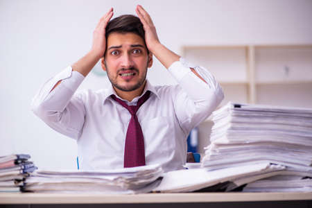 Young businessman employee unhappy with excessive work in the officeの写真素材