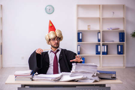 Funny young male employee magician and too much work in the officeの写真素材