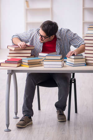 Young male student and too many books in the classroomの写真素材