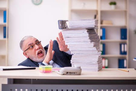 Old businessman employee unhappy with excessive work in the officeの写真素材