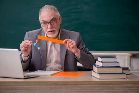 Old male teacher chemist in front of blackboardの写真素材