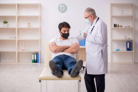 Young male patient visiting old doctor in vaccination conceptの写真素材