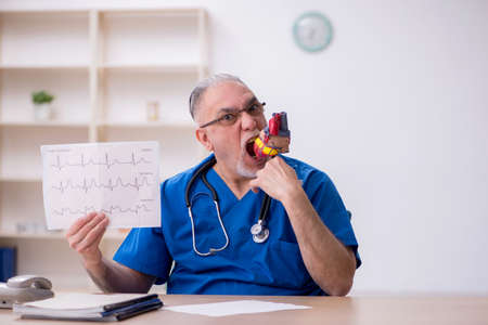 Old male doctor cardiologist working in the clinic