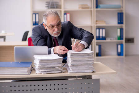 Aged male employee and too much work at workplaceの写真素材
