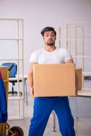 Young male contractor in movement concept at workplaceの写真素材
