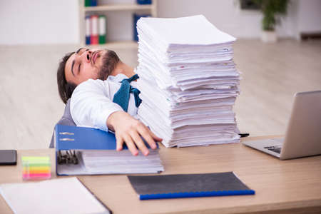 Young businessman employee unhappy with excessive work in the officeの写真素材