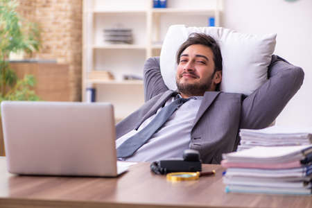 Young male employee in oversleeping conceptの写真素材