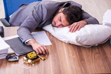 Young male employee in oversleeping conceptの写真素材