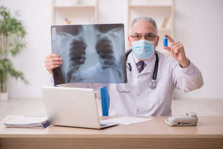 Old male doctor radiologist working in the clinic during pandemi