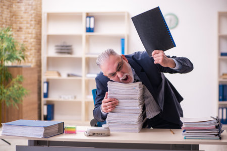 Old businessman employee unhappy with excessive work in the officeの写真素材
