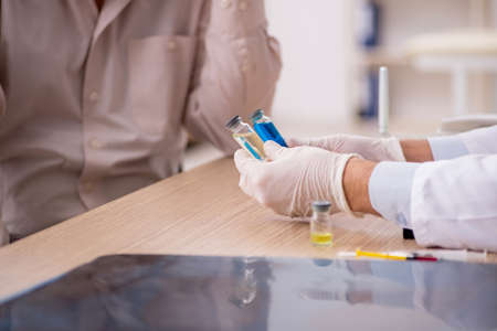 Old male patient visiting young male doctor in vaccination conce