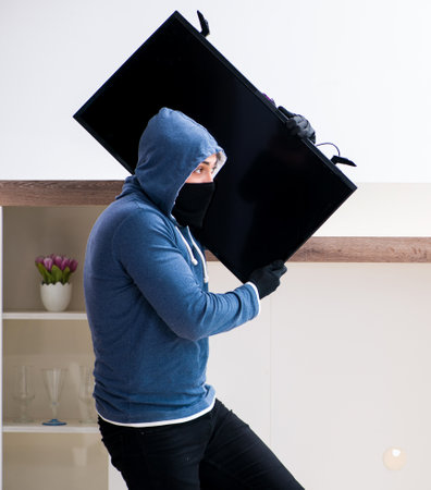 Man burglar stealing tv set from houseの写真素材