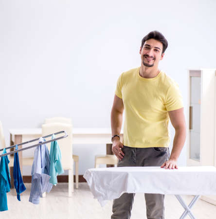 Handsome man husband doing clothing ironing at homeの写真素材