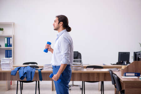Young male employee doing sport exercises during breakの写真素材