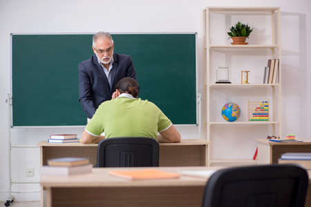 Aged teacher and young male student in the classroomの写真素材