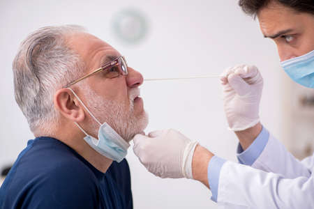 Old male patient visiting young male doctor otorhinolaryngologisの写真素材