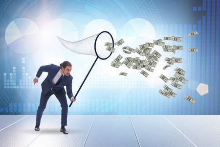 Young businessman catching dollars with landing netの写真素材