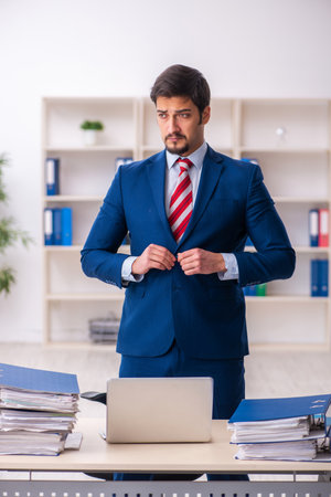 Young male employee unhappy with excessive work in the officeの写真素材