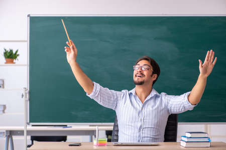 Young male teacher in front of blackboardの写真素材