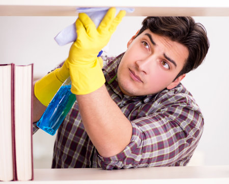 Man cleaning dust from bookshelfの写真素材