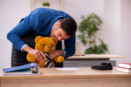 Young male employee and his toy bear boss in funny conceptの写真素材