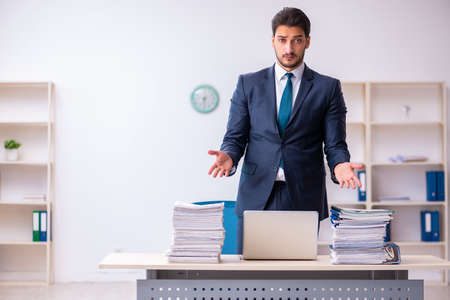 Young businessman employee and too much work in the officeの写真素材