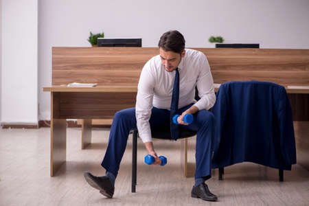 Young businessman employee doing sport exercises at workplaceの写真素材