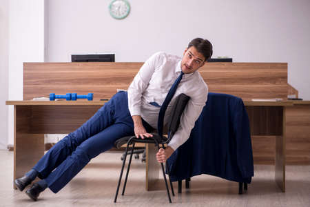 Young businessman employee doing sport exercises at workplaceの写真素材