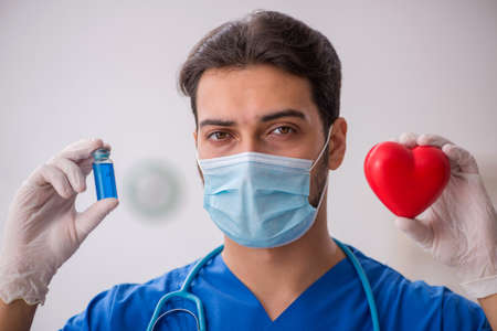 Young male doctor cardiologist working in the clinic during pandemic