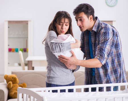 Young parents with their newborn baby near bed cotの写真素材