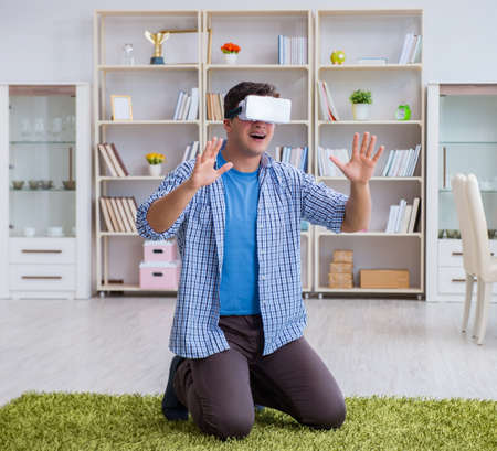 Man with virtual reality glasses playing at homeの写真素材