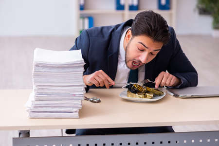 Young businessman employee eating alarm-clockの写真素材