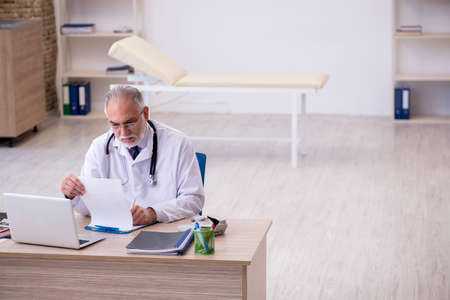 Old male doctor working in the clinicの写真素材