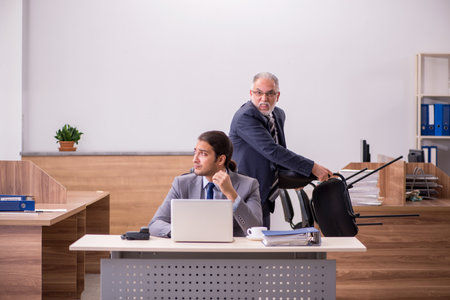 Old boss and young male assistant in the officeの写真素材