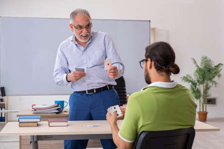 Old male teacher and young male student playing card in the classの写真素材