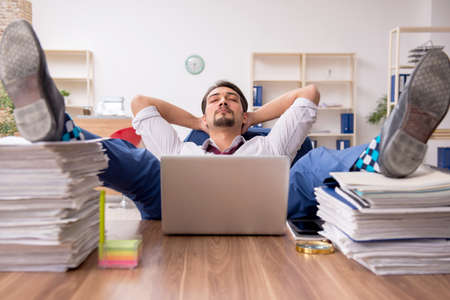 Young male employee and too much work in the officeの写真素材