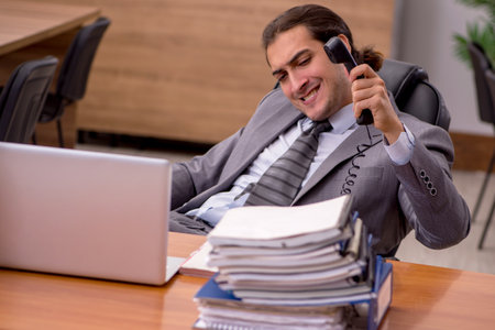 Young male employee and too much work in the officeの写真素材