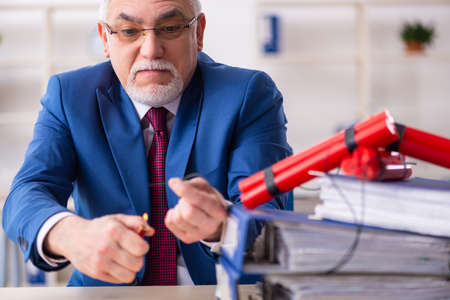 Old male employee with dynamite in the officeの写真素材