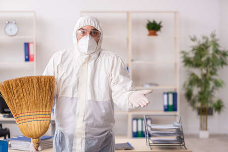 Old male contractor cleaning the office holding broom