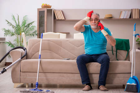 Old man cleaning the houseの写真素材